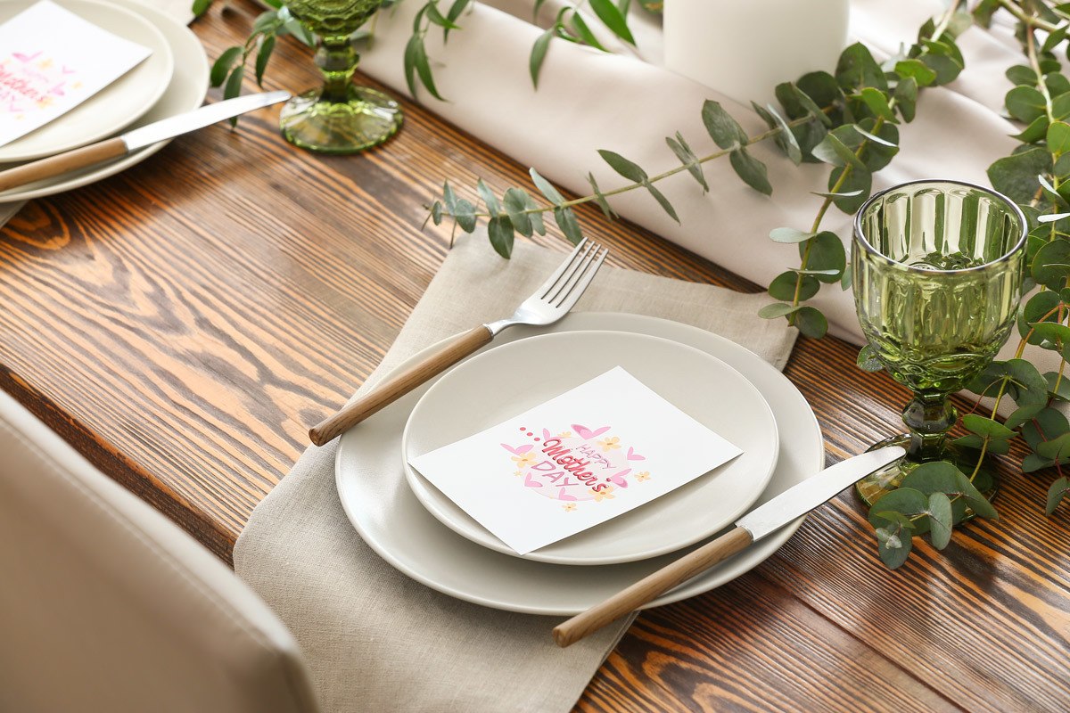 place setting at wood table with mothers day card place on top of plate