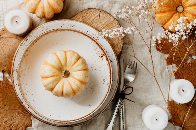 rustic thanksgiving table setting with white plates and a pumpkin