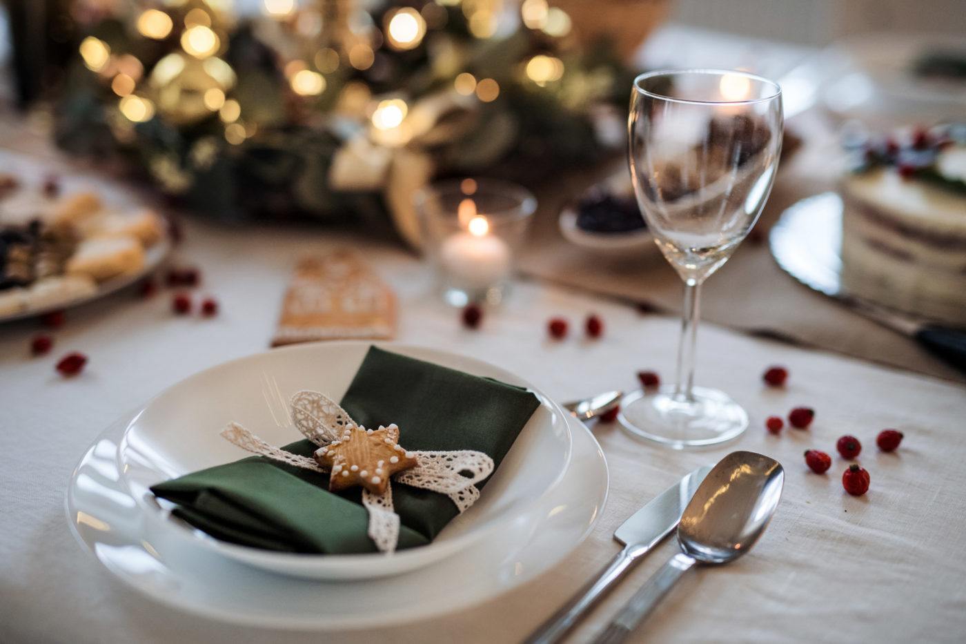 holiday table place setting with white plate and green napkin folded on top