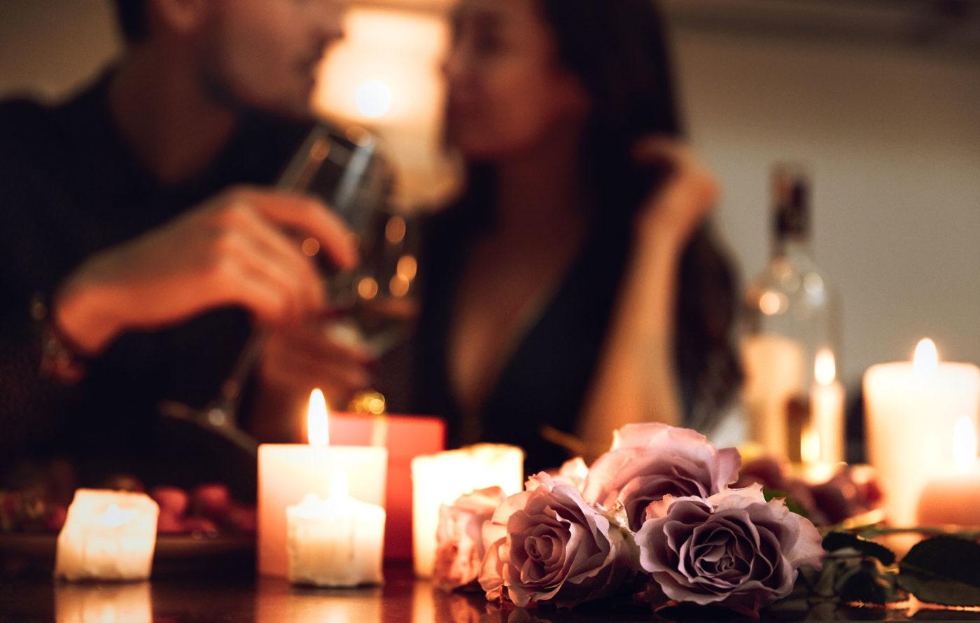 roses and candles sitting on table with blurred couple in background